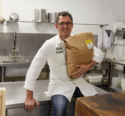 Owner Giovanni sits in a kitchen smiling