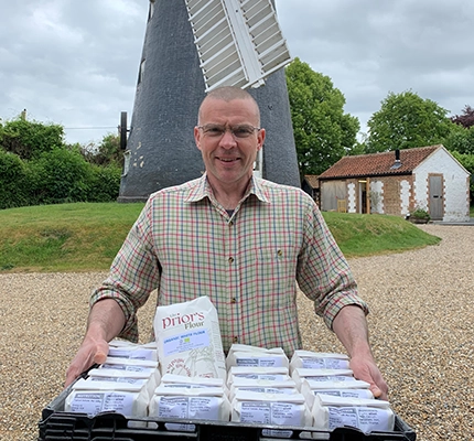 Man stands with priory flour infront of mill where the flour was prepared