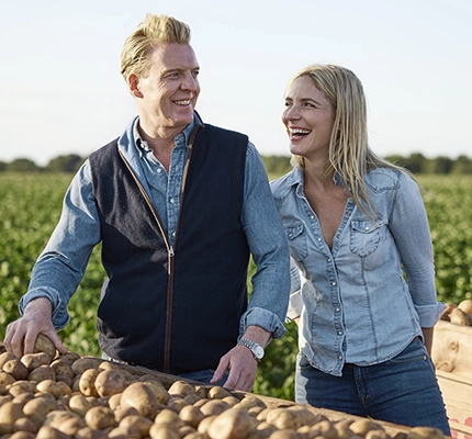 owners of Savoursmiths standing smiling next to their farms potatoes