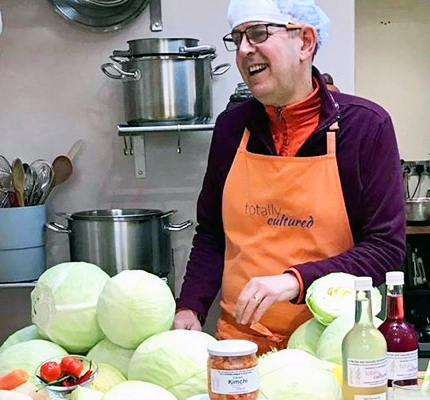 Local producer Kevin is in the kitchen surrounded by fermented foods and cabbages